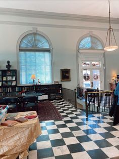 a living room with black and white checkered flooring next to two large windows