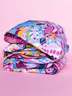 three sheets folded on top of each other in different colors and patterns, with pink background