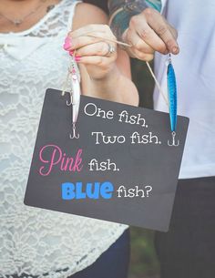 a woman holding a sign that says, one fish two fish pink fish blue fish?