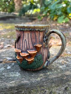 a coffee cup with mushrooms growing out of it on top of a tree stump in the woods