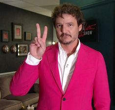 a man in a pink suit making the peace sign