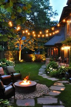 an outdoor fire pit in the middle of a yard with lights strung over it and lawn furniture