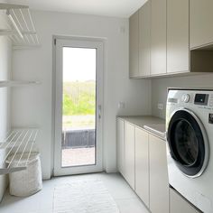 a washer and dryer in a white room with open shelves on the wall