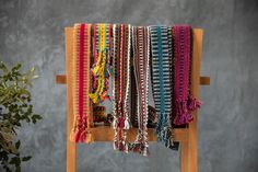 a wooden chair with several different colored bracelets on it's arm and a potted plant in the background