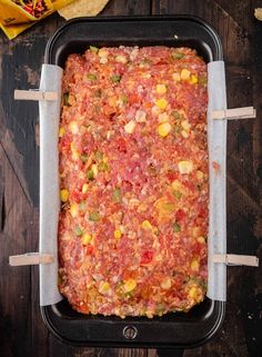 a square casserole dish with corn on the cob and tortilla chips