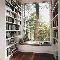 a window seat in the corner of a room with bookshelves full of books