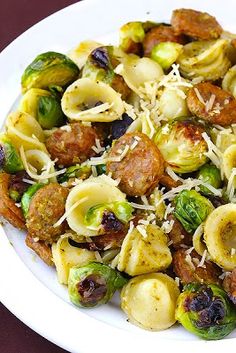 pasta with sausage, brussels sprouts and broccoli on a white plate