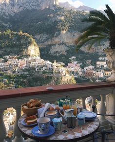 a table with food and drinks on top of it near a balcony overlooking the city