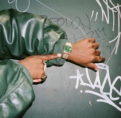 a person wearing a green leather jacket and gold watch