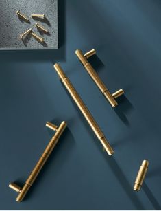 three gold - plated metal objects are laying on a blue surface and one is in the foreground