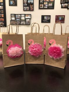 three paper bags with pink flamingos on them sitting on a table in front of pictures