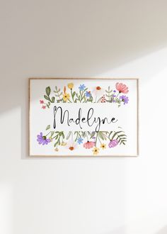 a white wall with flowers and the words madelyne on it