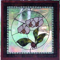 a stained glass window with white flowers on the inside and green leaves in the outside