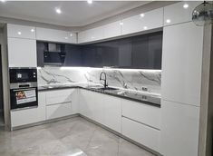 an empty kitchen with marble counter tops and white cupboards on the walls, along with black appliances