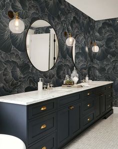 a bathroom with two sinks, mirrors and lights on the wall next to each other