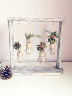 an old window frame is decorated with hanging plants and pine cones for christmas ornament decorations