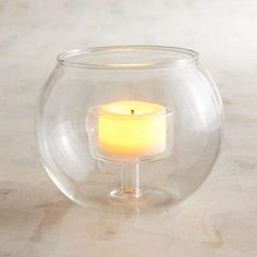 a lit candle in a glass bowl on a table