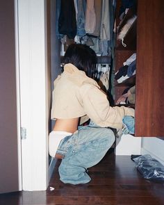 a person kneeling on the floor in front of a closet