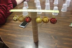 a group of christmas ornaments hanging from a pole on a table with a ruler in front of them