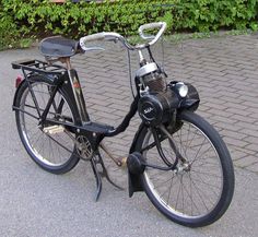 a black bicycle parked on the side of a road next to bushes and shrubbery