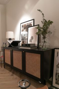 a living room with an entertainment center and pictures on the wall, plants in vases