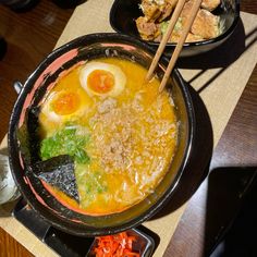 a bowl of ramen with chopsticks on the side and another bowl full of food