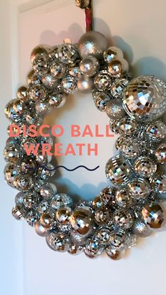 a wreath made out of silver balls hanging on a door with the words disco ball wreath