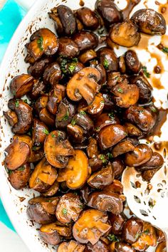 cooked mushrooms with brown sauce in a white bowl on a blue and white tablecloth