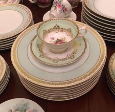 a table topped with lots of plates covered in floral designs and gold trimmings