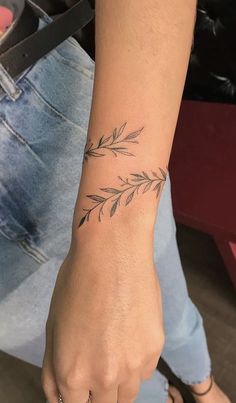 a woman's hand with a small tattoo on her left wrist and an olive branch in the middle