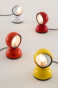 four different colored lamps sitting on top of a white table next to eachother