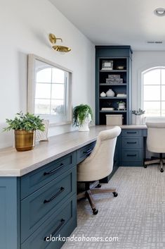 a home office with blue cabinets and white desks in the corner, along with two chairs