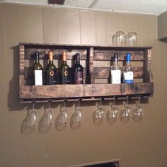 several wine glasses and bottles are hanging on a wooden rack with wine glasses in it