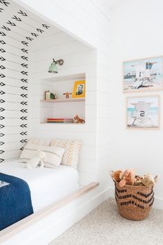 a bedroom with white walls and black and white patterns on the wall, along with a basket full of stuffed animals