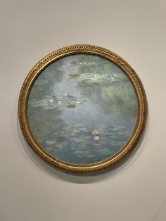 an oval painting hanging on the wall with water lillies in it's center