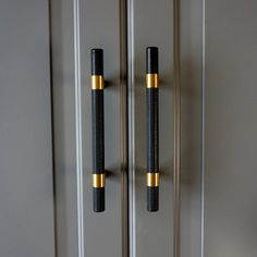 two black and gold door handles in front of a gray wall with white trim on it