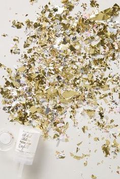 gold and silver confetti sprinkles on a white table with a bottle