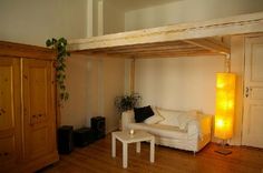 a white couch sitting under a wooden beam in a living room next to a lamp