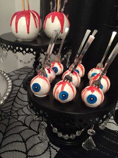 some white and red cake pops with blue eyes on them sitting on a black table