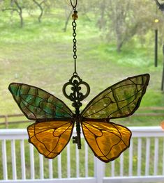 a stained glass butterfly hanging from a chandelier in front of a white porch