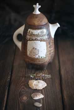 a tea pot sitting on top of a wooden table next to some rocks and pebbles