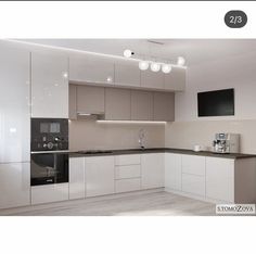 an empty kitchen with white cabinets and black counter tops is shown in this image, there are three lights on the ceiling