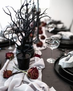 the table is set with black plates and flowers