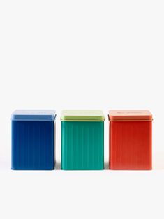 three different colored containers sitting next to each other