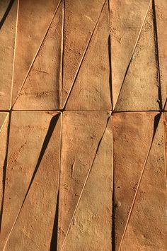 an orange cat sitting on the ground next to a brick wall with lines drawn across it