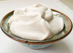 a bowl filled with whipped cream sitting on top of a white tablecloth covered table