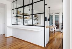 an open kitchen and dining area with wood floors, white walls and black framed windows