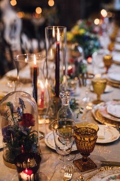 the table is set with candles, plates and glass vases for dinner guests to enjoy