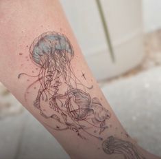 a woman's leg with a jellyfish tattoo on her left arm and an octopus in the background