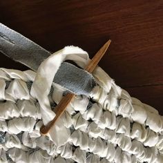 a close up of a piece of cloth on a wooden surface with two knitting needles sticking out of it